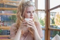 Smiling blonde woman drinking coffee hot cappuccino and looking at camera. Pretty woman with cup of coffee Royalty Free Stock Photo