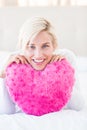 Smiling blonde woman holding heart pillow Royalty Free Stock Photo