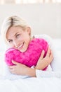 Smiling blonde woman holding heart pillow Royalty Free Stock Photo