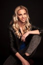 Smiling blonde woman in leather jacket resting on a chair Royalty Free Stock Photo