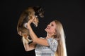 A smiling blonde woman lifts her dog up and they look into each other& x27;s eyes. Long hair. Black background. Royalty Free Stock Photo