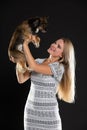 A smiling blonde woman lifts her dog up and they look into each other& x27;s eyes. Long hair. Black background. Royalty Free Stock Photo