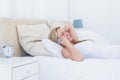 Smiling blonde woman lying in bed phoning Royalty Free Stock Photo