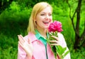Smiling blonde woman with peony flower outdoors. Beautiful girl in garden. Royalty Free Stock Photo