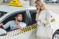 smiling blonde woman talking by smartphone and looking at male driver sitting