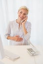 Smiling blonde woman using computer and phoning Royalty Free Stock Photo