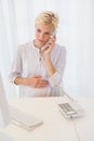 Smiling blonde woman using computer and phoning Royalty Free Stock Photo