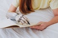 Woman writes in paper notebook with bionic arm lying on bed Royalty Free Stock Photo