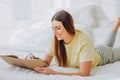 Woman writes in paper notebook with bionic arm lying on bed Royalty Free Stock Photo