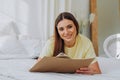 Woman writes in paper notebook with bionic arm lying on bed Royalty Free Stock Photo