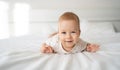 Smiling blue-eyed baby girl four months old lying on the bed looking at the camera, baby care, toodler in the bedroom at Royalty Free Stock Photo