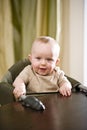 Smiling blue-eyed baby in highchair