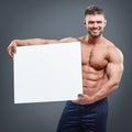 Smiling bodybuilder holding blank white poster