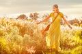 Smiling bohemian girl in yellow dress with guitar dance on the field at sunset warm light Royalty Free Stock Photo