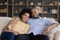Smiling bonding mixed race couple resting on couch. Royalty Free Stock Photo