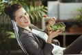 smiling bookkeeper woman in green office eating salad