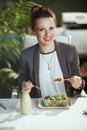 smiling bookkeeper woman in green office eating salad