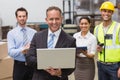 Smiling boss using laptop in front of his employees