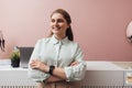 Smiling boutique owner standing at counter with crossed arms looking away