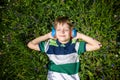 Smiling boy with arms under head lay under the sun on the green grass and listening music after school. Photo from above. Nature Royalty Free Stock Photo