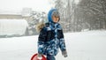 A smiling boy carries his sleds up a snow-covered hill, ready for an exciting ride down. Joy and wonder of winter playtime Royalty Free Stock Photo