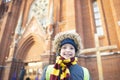 a smiling boy, a child in warm winter clothes, stands near the Catholic Church. Royalty Free Stock Photo