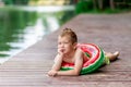 A smiling boy with a circle in the form of a watermelon lies on the lake in summer, a child`s rest in the village, a happy Royalty Free Stock Photo