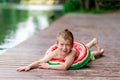 A smiling boy with a circle in the form of a watermelon lies on the lake in summer, a child`s rest in the village, a happy Royalty Free Stock Photo