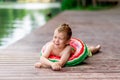 A smiling boy with a circle in the form of a watermelon lies on the lake in summer, a child`s rest in the village, a happy Royalty Free Stock Photo