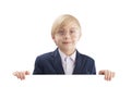 Smiling boy with empty white paper board and laughs. Cute blond boy peeking out from behind white board. Space for text Royalty Free Stock Photo