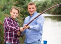 Smiling boy fishing with man on freshwater lake