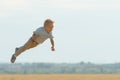 Smiling boy flying in the air, playing on field Royalty Free Stock Photo