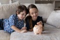 Smiling boy and girl putting coin into pink piggy bank Royalty Free Stock Photo