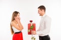Smiling boy giving to his girlfriend a gift and a rose, girl surprised