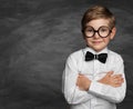 Smiling Boy in Glasses over Blackboard. Happy stylish Child in black Bow Tie and white Shirt over dark background. Cute Elementary Royalty Free Stock Photo