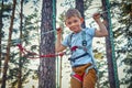 Smiling boy is having fun in an extreme rope park.