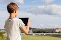 Smiling boy hold tablet PC. Outdoor. Blue sky and city background. Back to school, education, learning, technology Royalty Free Stock Photo