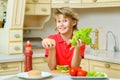 Smiling boy holding a hamburger bun and salad in