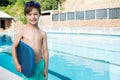 Smiling boy holding kickboard at poolside Royalty Free Stock Photo