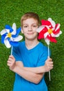 Smiling boy holding pinwheels over grass close up