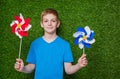 Smiling boy holding pinwheels over grass