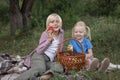 Smiling boy and little girl with apples in hand sit on lawn in garden. Picnic for children on warm summer day Royalty Free Stock Photo