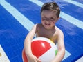 Smiling boy playing with ball at swimming pool. Royalty Free Stock Photo