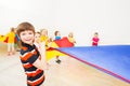 Smiling boy playing parachute with friends in gym Royalty Free Stock Photo
