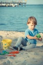 Smiling boy playing on sand at beach. Summer, vacation and relaxation time concept Royalty Free Stock Photo