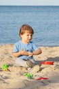 Smiling boy playing on sand at beach. Summer, vacation and relaxation time concept Royalty Free Stock Photo