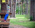 Smiling boy rides a zip line. happy child on the zip line. The kid passes the rope obstacle course