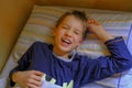 Smiling boy`s facial expression. cute blonde boy in blue pajama smiling, waking up in bed in the morning close-up. Kids bedroom. R Royalty Free Stock Photo