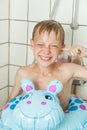 Smiling boy showers with blue inflatable toy