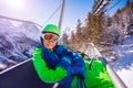 Smiling boy sit on the ski chair lift over forest Royalty Free Stock Photo
